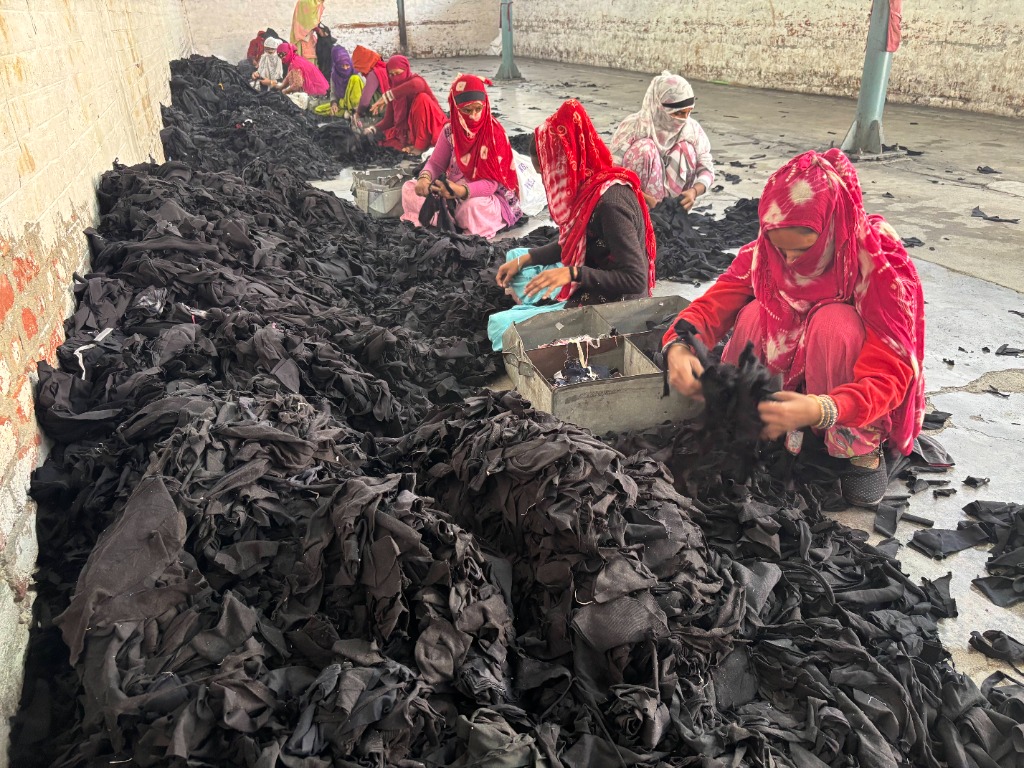 Women textile recycling workers sorting pre-consumer black fabric cutting waste